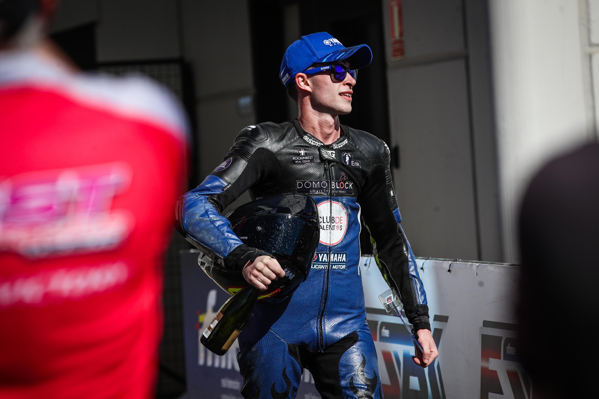 Héctor Gris en el paddock con el casco bajo el brazo y la botella del podio